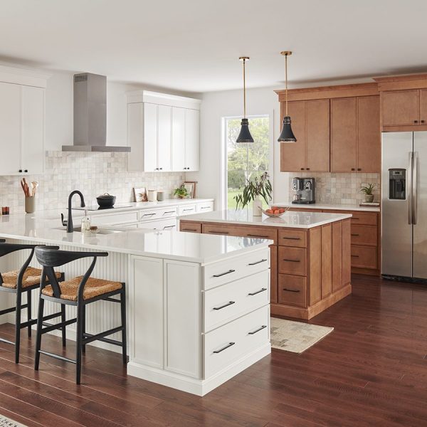 a kitchen with white cabinets and brown cabinets and a stainless steel refrigerator